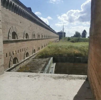 En blick ut genom ett fönster över fästningens murar och det omkringliggande landskapet.