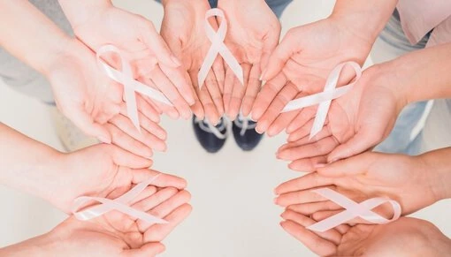 Flera händer hålls samman, var och en med ett rosa band för att symbolisera kampen mot cancer och vikten av gemenskap.